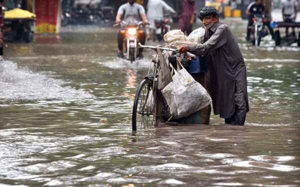 Elderly Man Navigates Flooded Road with Household Items Elderly Man Navigates Flooded Road with Household Items