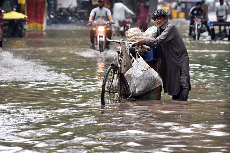 Elderly Man Navigates Flooded Road with Household Items Elderly Man Navigates Flooded Road with Household Items
